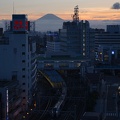 Un train <em>N'EX</em> quitte la gare devant le mont <em>Fuji</em> dans le <em>bleu</em> du crépuscule