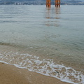 Vague s'échouant sur la plage devant le <em>grand torii flottant</em> d'Itsukushima