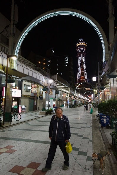 Homme promenant son chien la nuit à Shinsekai à Osaka et tour Tsutenkaku