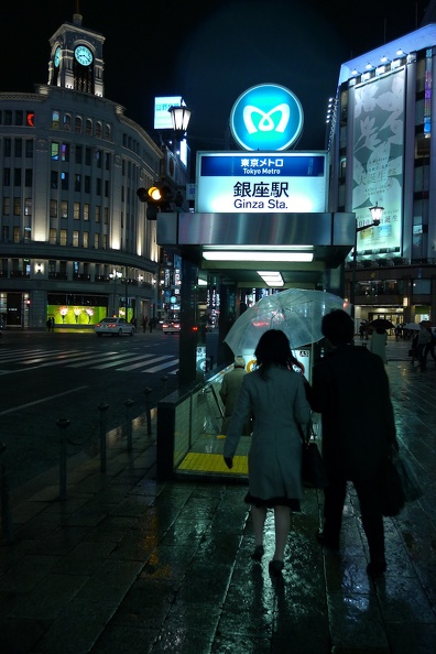 Couple protégé d'un parapluie entrant dans la bouche du métro Ginza à Tokyo